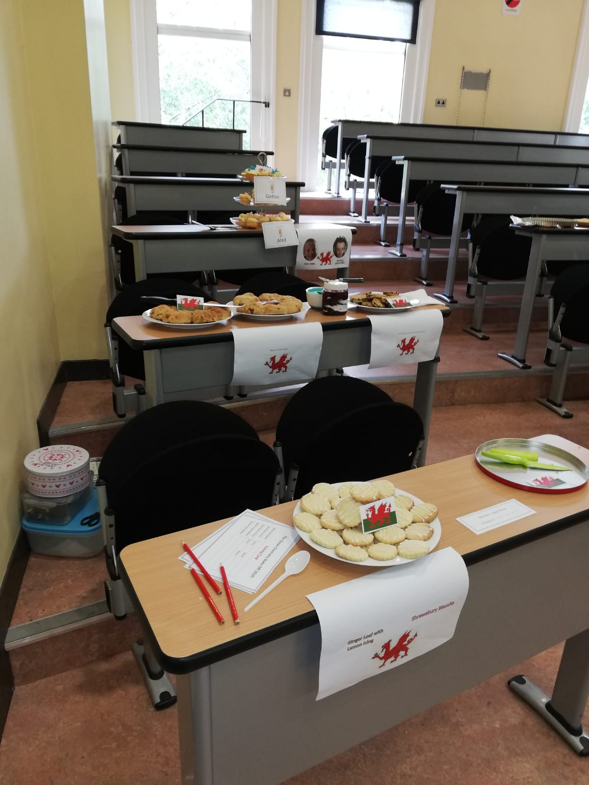 Cakes and biscuits displayed on Lecture theatre tables labelled with Welsh Flags