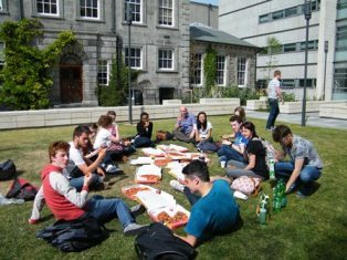 students eating pizza on the grass