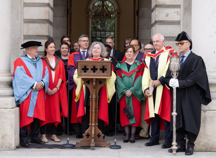 Provost, Dr Linda Doyle, surrounded by Senior Fellows of the College, reads out the names of new Fellows and Scholars from the steps in fronf of the Public Theatre in Front Square